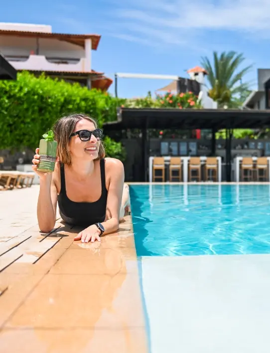 Mujer disfrutando de una bebida refrescante junto a la piscina del Finch Bay Hotel, reflejando el lujo de Casa Gangotena Boutique.