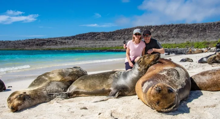 Tourists alongside sea lions on Santa Fe Island, Galapagos during a Casa Gangotena tour.