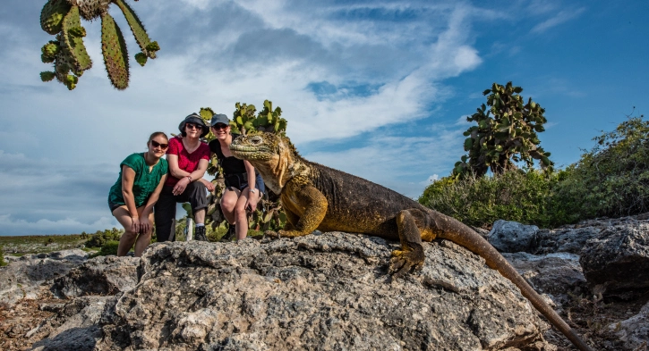 Tourists posing near a land iguana on South Plaza Island during a Casa Gangotena Galapagos tour.