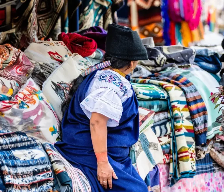 Woman showcasing textiles during cultural tour in Otavalo.